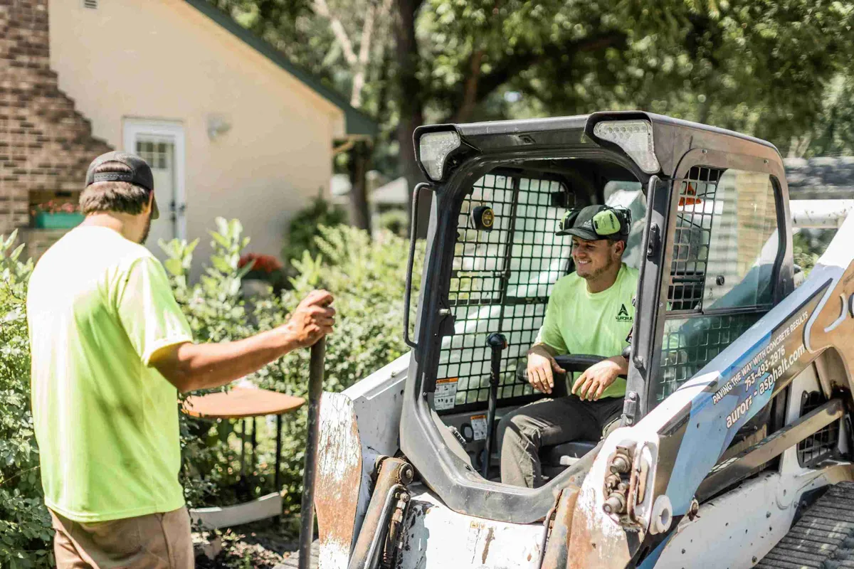 Aurora crew member operating a skid steer at a home
