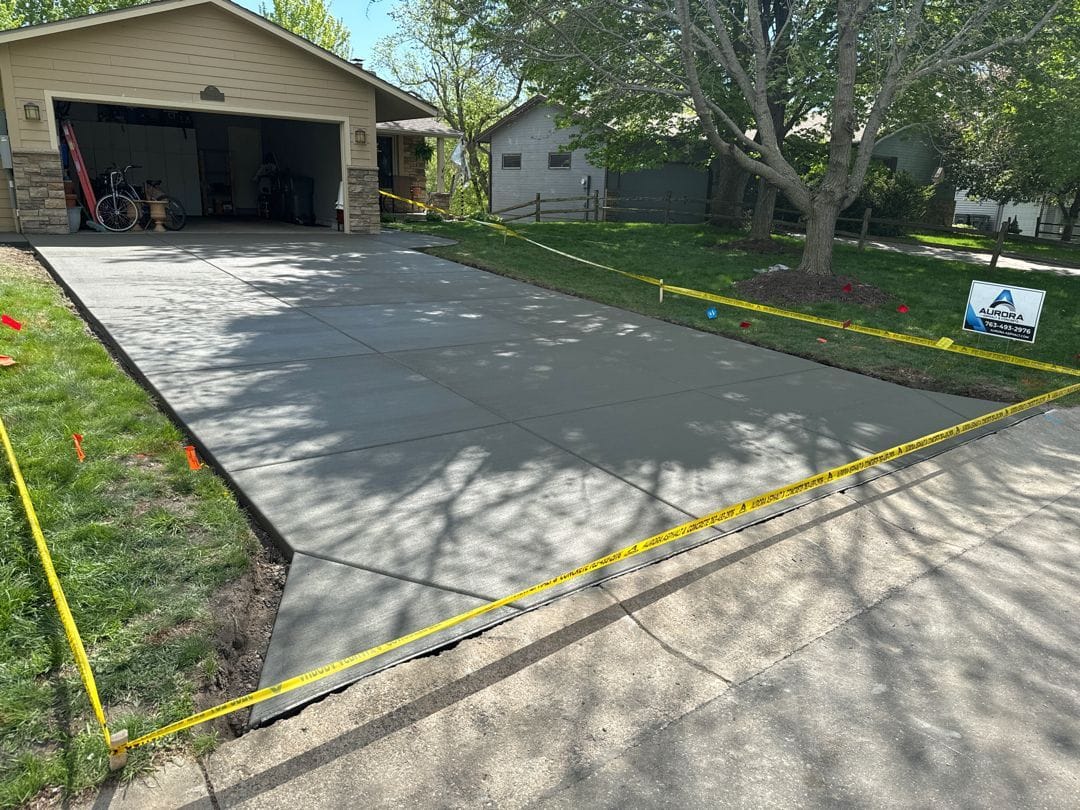 Concrete driveway repair just completed at a suburban home, with fresh concrete taped off while it cures.
