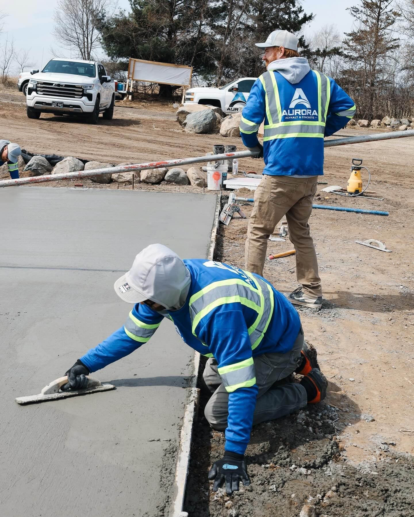 Two Aurora concrete driveway contractor crew members finishing a fresh concrete pour.