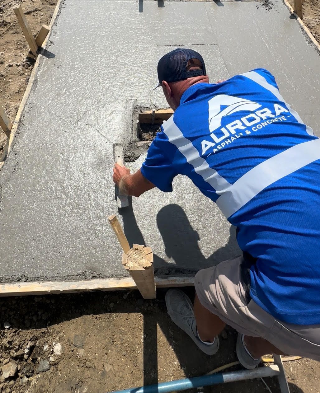 Aurora installer hand-finishing wet concrete during a concrete driveway installation.