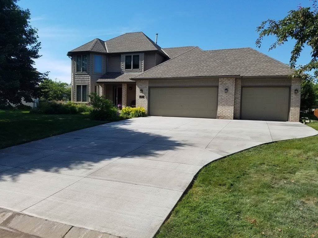 Finished concrete driveway installation at a two-story home with a three-car garage.