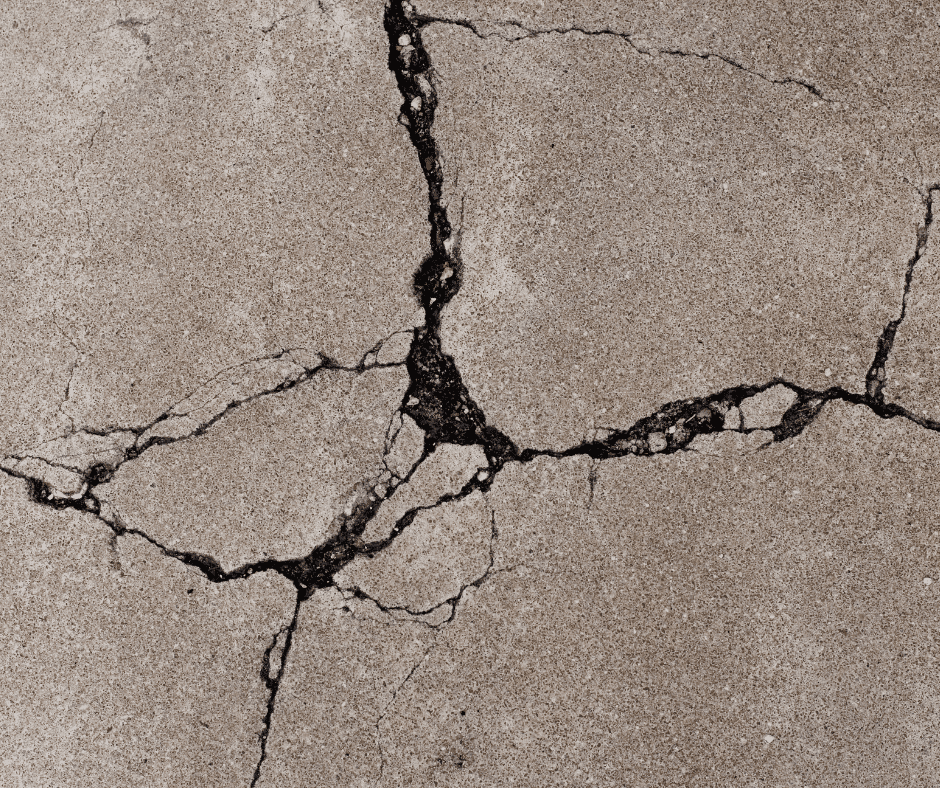 Close-up of wide cracks in concrete that need cracked concrete driveway repair.