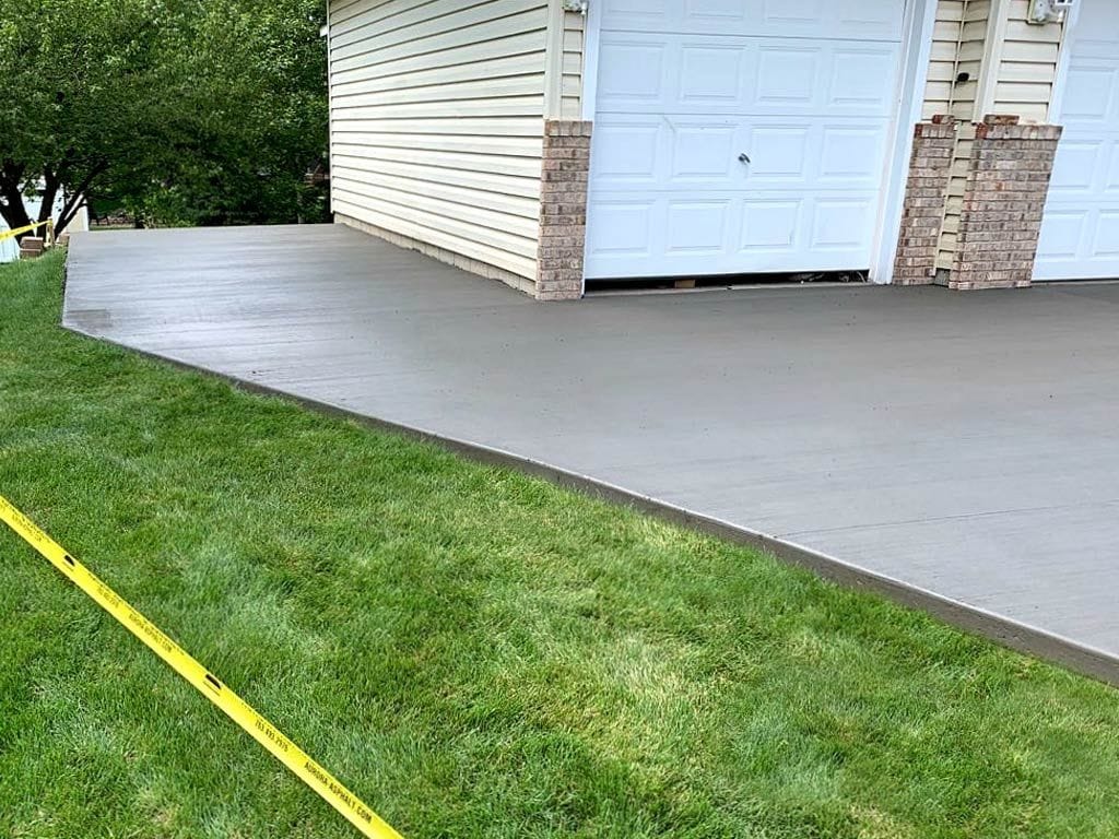 Concrete pad widening a driveway in front of a garage, built by a driveway extension contractor.